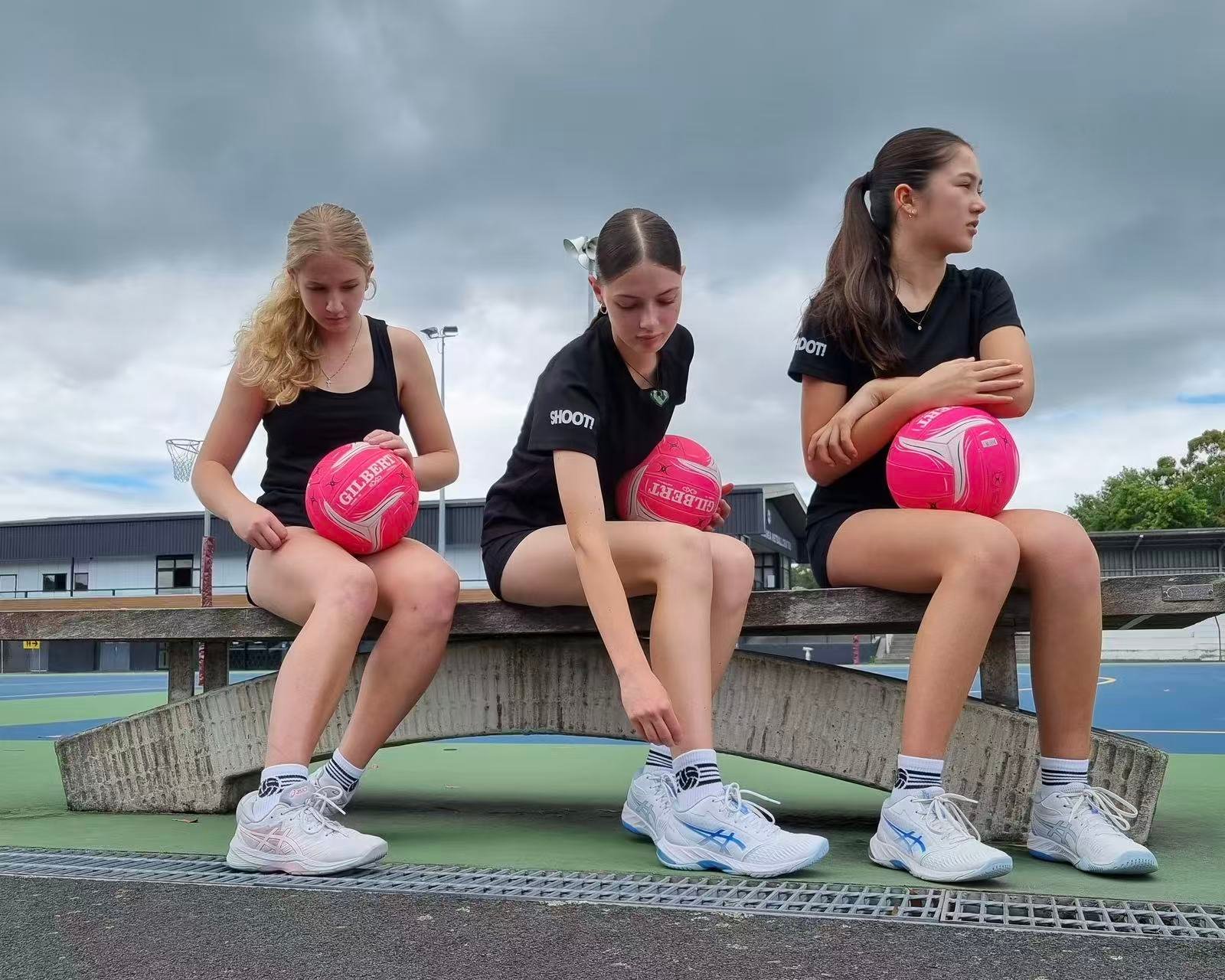 Female netball players wearing custom white ankle athletic socks on an outdoor court.