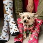 Two people wearing custom dog photo socks in blue and cream during a sunny outdoor trip.