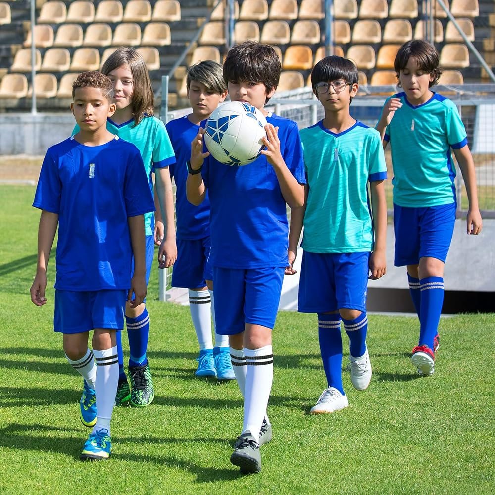 Youth soccer players wearing custom knee high athletic socks on a grass field.