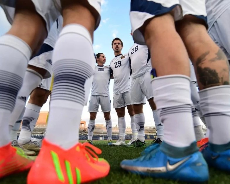 Soccer team wearing white custom soccer grip socks and football boots during a pre-match huddle on the field.