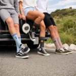 Three people wearing custom embroidered crew socks in blue, charcoal and dusty rose.