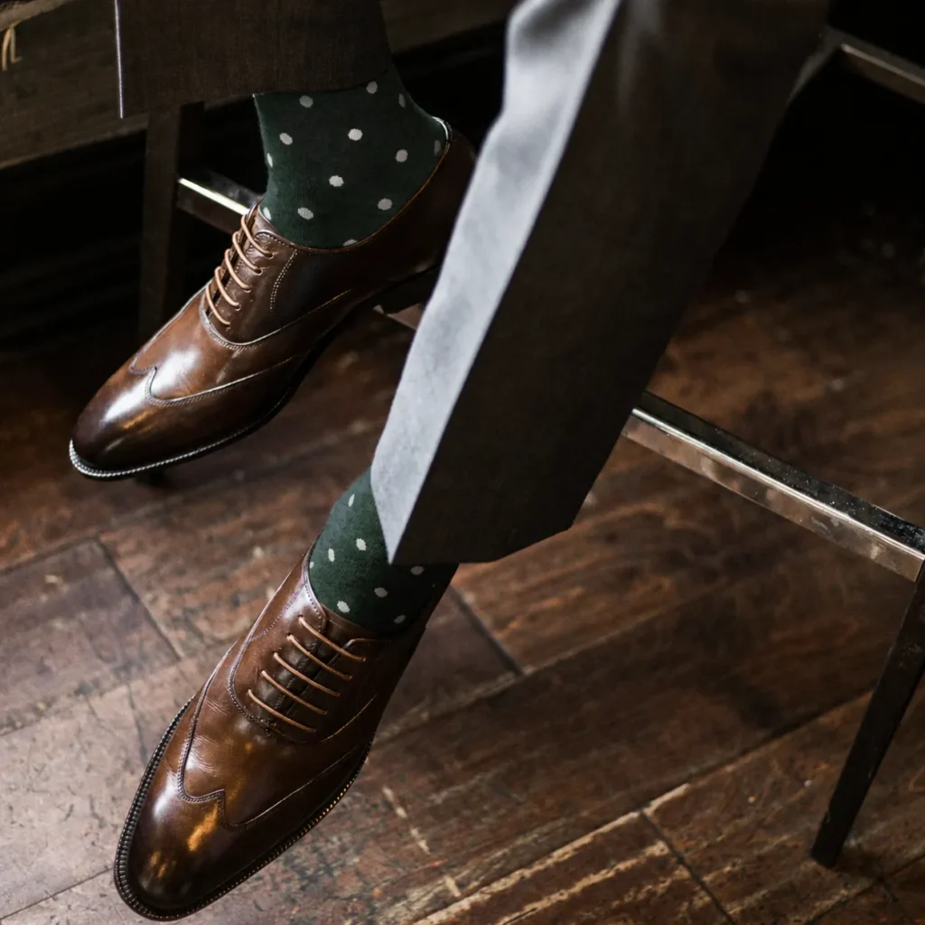 Custom green polka dot crew dress socks worn with brown Oxford leather shoes.
