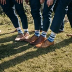 Group of men wearing matching blue striped custom quarter crew socks with brown leather shoes outdoors.