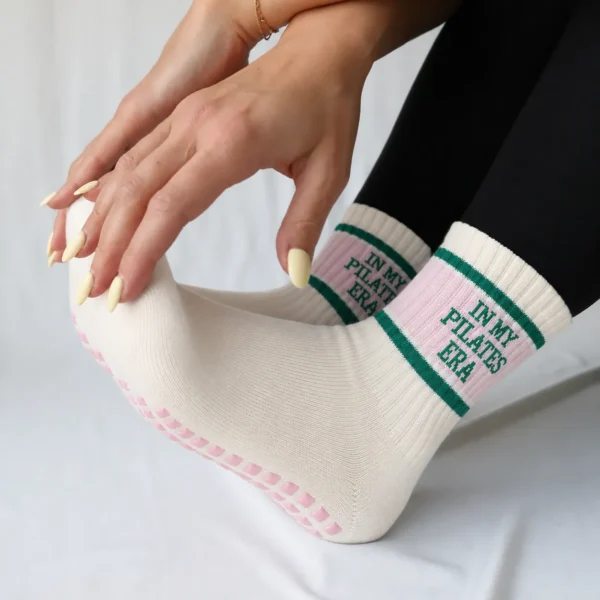 Close-up of cream Pilates grip socks with pink panels, green stripes, and pink silicone sole grips.