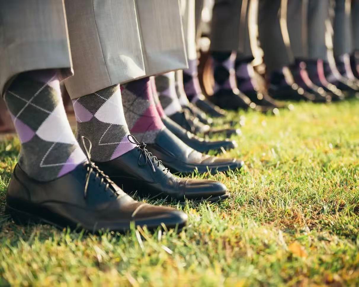 Groomsmen wearing custom over the calf dress socks with gray and lavender argyle patterns.