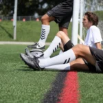Soccer players wearing white custom grip socks with black chevron details on a football field.