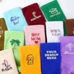 Colorful custom embroidered crew socks with names, dates and small logo designs.