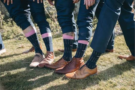 Groomsmen wearing custom navy crew dress socks with pink cuffs and subtle dot patterns.