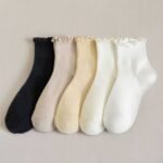 Custom ruffle socks in black, beige, yellow, cream, and white with delicate scalloped cuffs.
